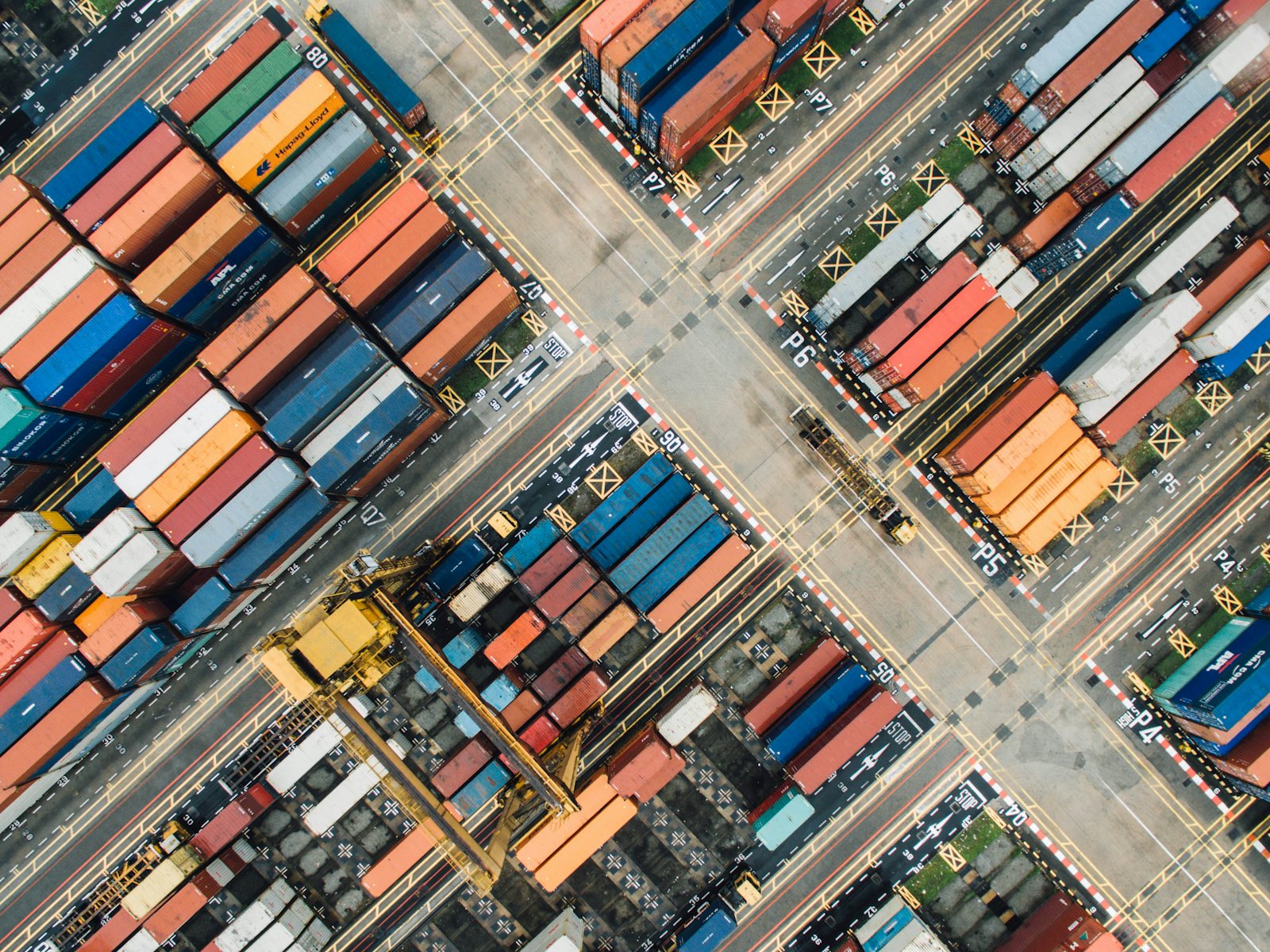 Aerial view of a container terminal, freight containers stacked in rows along the quay.